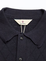 Close-up of the BGwally Diamond Polo in Dark Navy, a lightweight knit polo with a collar and buttons. Inside the collar, the label reads Blue de Gênes beneath a small shield logo. Crafted from a cotton-linen blend, this polo features a subtle diamond-knit pattern.