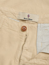 Close-up of the BGpalco Rodas Pants in Pale Khaki by Blue de Gênes, crafted from a beige cotton-hemp blend. Features include a wooden button, partially unzipped fly, and a waistband label with the Blue de Gênes shield logo. The visible inside lining showcases the refined details of these smart-casual trousers.