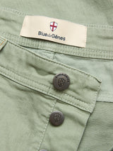 Close-up of BGpaulo Pavia Pant in Shadow Green by Blue de Gênes, with metallic shield-logo buttons, branded label, and red and white emblem.