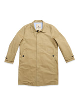 The BGjacques Coat in Pale Khaki by Blue de Gênes features a single collar, buttoned front, side pockets with buttons, and buttoned cuffs—crafted from heavy cotton fabric and presented laid flat on a white background for a classic workwear-inspired look.