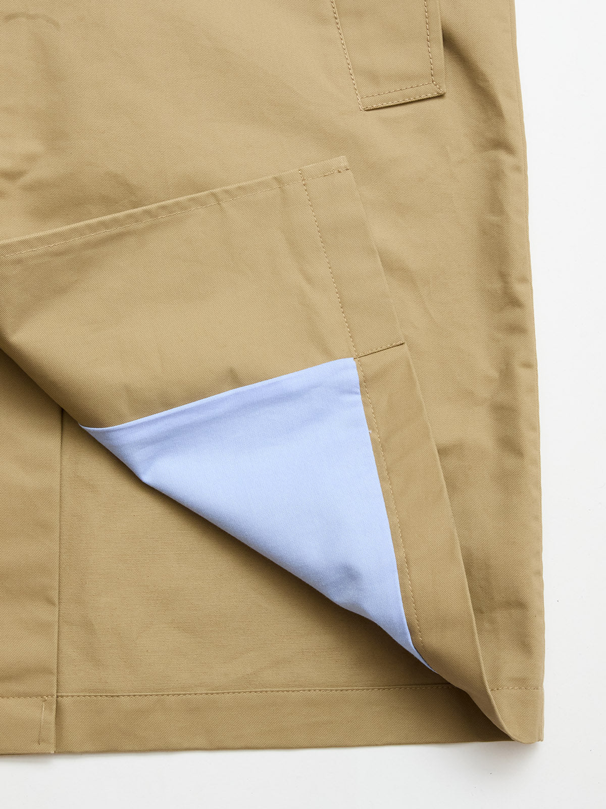 A close-up of the BGjacques Coat in Pale Khaki by Blue de Gênes, crafted from heavy cotton, highlights a large pocket turned to show its light blue inner lining.