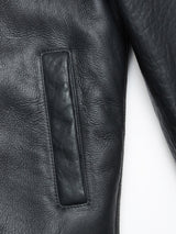 Close-up of the Rufo Shearling Jacket - Scarab by Blue de Gênes, highlighting a side pocket and sleeve. The black leather showcases a textured, slightly wrinkled finish that reflects the refined craftsmanship synonymous with men’s luxury outerwear.