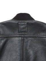 Back view of the Rufo Shearling Jacket - Scarab by Blue de Gênes in black natural sheepskin leather, featuring a ribbed knit collar and a stitched rectangular patch below the collar. The textured finish of the leather, with its visible seams and natural creases, makes this jacket an exceptional choice in men’s luxury outerwear.