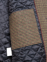 A close-up of the Massone Check Coat - Multi Check by Blue de Gênes, featuring a quilted black design with a brown and black houndstooth pocket in Melton weave, plus a white rectangular tag on the lining.