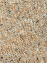 Close-up of the Honshu Crewneck Knit - Fungi by Blue de Gênes, a beige lambswool blend sweater featuring specks of orange, black, and white, highlighting its textured stitches and soft, cozy appearance.