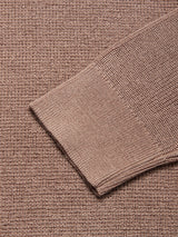 A close-up of the Porto Knit - Fungi crewneck sweater sleeve by Blue de Gênes, featuring a ribbed brown menswear design, lying diagonally on a matching textured brown fabric background.