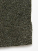 A close-up of the textured fabric of the Blue de Gênes Malakka Polo Knit - Army, highlighting its dark green wool blend and a visible seam, shown against a white background.