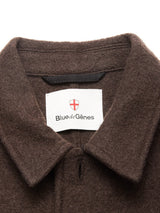 Close-up of the collar on the Kojima Wool Jacket - Chocolate by Blue de Gênes, showing a neck label with the brand name and a red and white shield emblem.
