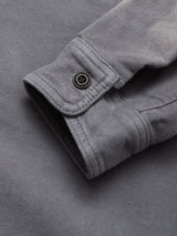 A close-up of the cuff on the Nagano Overshirt - Dark Slate by Blue de Gênes, featuring black button detail and highlighting its garment-dyed Moleskin cotton texture and stitching.