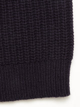 Close-up of the Yomaha Halfzip Knit in Navy by Blue de Gênes, featuring a dark, ribbed knit fabric with vertical textured lines, possibly part of the sweater’s edge, shown against a light background.