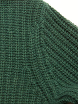 Close-up of a green, ribbed knitted fabric, likely part of the Yomaha Halfzip Knit - Scarab by Blue de Gênes, highlighting the detailed texture and pattern of the wool blend stitches.