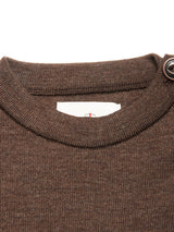 Close-up of the neckline of the Toyama Knit L/S - Brown by Blue de Gênes, showing a visible white tag inside and a button on the right shoulder.