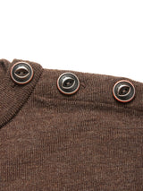Close-up of the Blue de Gênes Toyama Knit L/S in brown, featuring three dark brown buttons with contrasting rims and text along the shoulder seam.