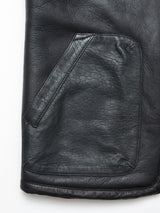 Close-up of the Saga Shearling Gilet - Scarab by Blue de Gênes, showcasing the luxurious black leather pocket with visible texture and stitching against a plain white background, evoking the refined quality of German Merino sheepskin craftsmanship.