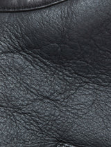Close-up of the black leather material used in the Blue de Gênes Saga Shearling Gilet - Scarab, potentially crafted from premium German Merino sheepskin. The image highlights the natural texture, fine wrinkles, and distinctive grain patterns; certain areas exhibit a subtle shine and smoothness—an ideal finish for this luxurious reversible shearling gilet.