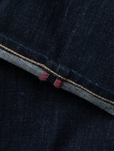 Close-up of BGvinci Girisha Rinse Jeans by Blue de Gênes in dark blue comfort stretch denim, featuring visible orange stitching and a red selvedge edge, highlighting inside and outside details of the rinse wash five-pocket style.