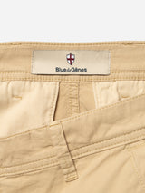 Close-up of BGmenzo Vecchio Chino in Pale Khaki by Blue de Gênes, showing the waistband, belt loops, and a label with a red and white crest, highlighting the vintage chino style.