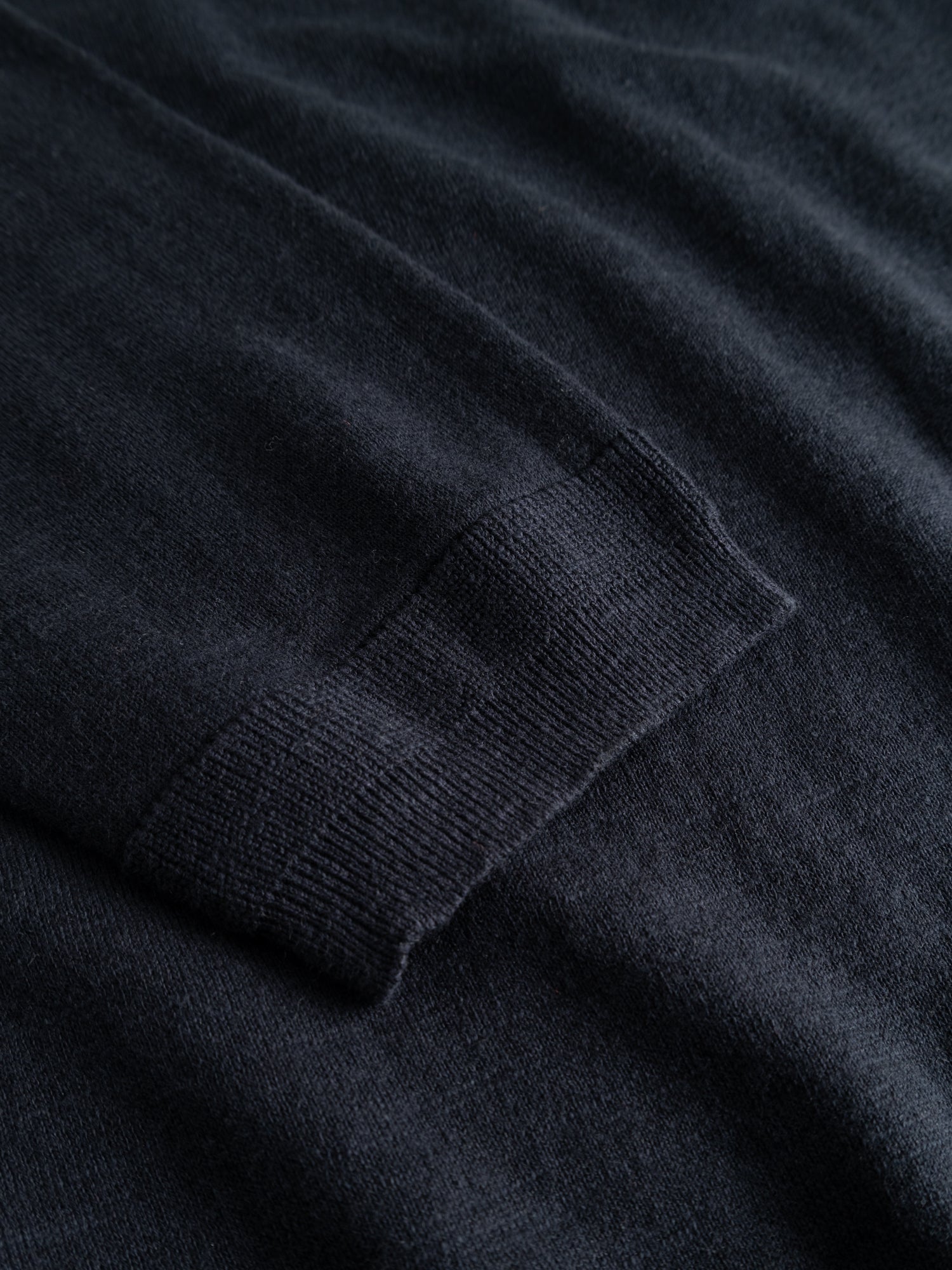 A close-up of the BGmonty Knit in Dark Navy by Blue de Gênes, featuring a laid-flat sleeve that highlights the ribbed cuff and soft cotton linen blend texture.