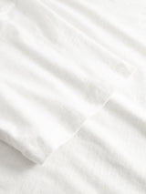 Close-up of a plain white BGoscar T-Shirt - Snow Fall by Blue de Gênes on a white textured fabric background, highlighting its soft and smooth 100% cotton material.