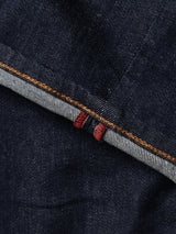 Close-up of BGrepi Dai V Dark V2 Jeans by Blue de Gênes, made from dark blue comfort stretch denim with a visible selvedge edge featuring a white strip, red line, and orange stitching in classic slim-fit style.