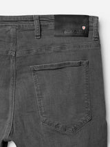 Close-up of the back of Blue de Gênes BGrepi Giulio Light V2 Jeans in grey denim, featuring a single back pocket, comfort stretch fabric, a black leather patch with logo, and a red and white shield emblem by the waistband.