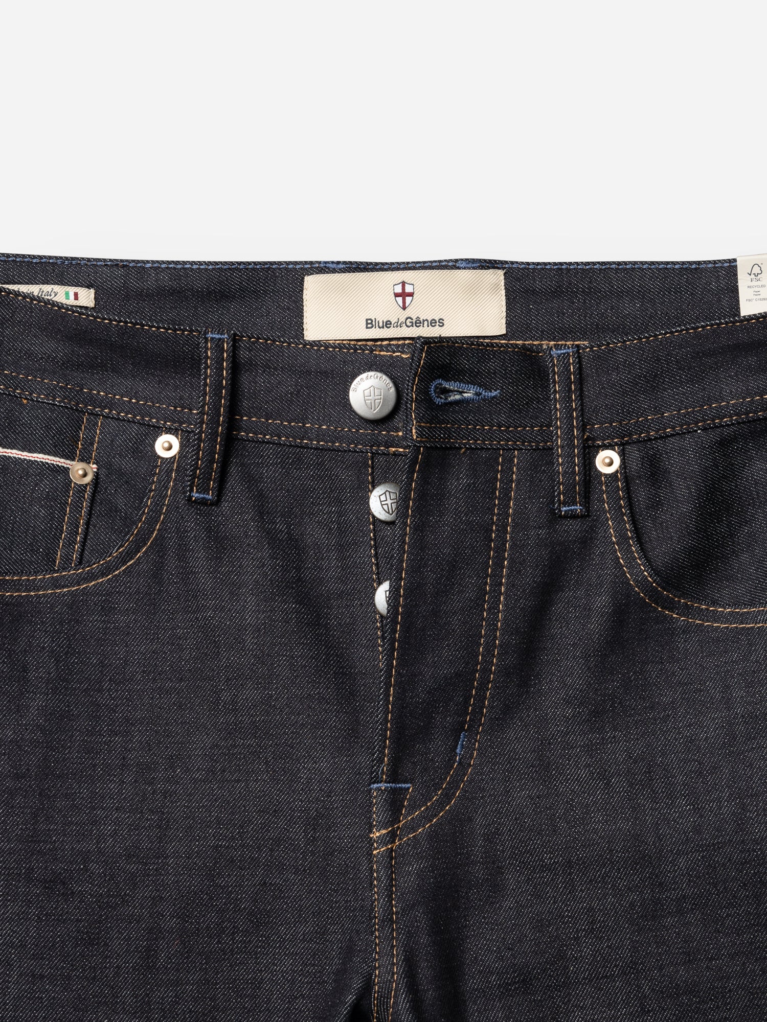 Close-up of the BGgiacomo Selvedge V2 Jeans in raw dark blue denim, featuring a button fly, visible stitching, and a Blue de Gênes label above the waistband. Expertly crafted in Italy, these relaxed fit jeans showcase timeless style and superior craftsmanship from Blue de Gênes.
