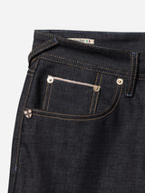 Close-up of the front pocket area of BGgiacomo Selvedge V2 Jeans - Raw Denim by Blue de Gênes, featuring dark blue rigid denim with brown stitching, metal rivets, and an Italian flag tag near the waistband—showcasing authentic made-in-Italy craftsmanship.