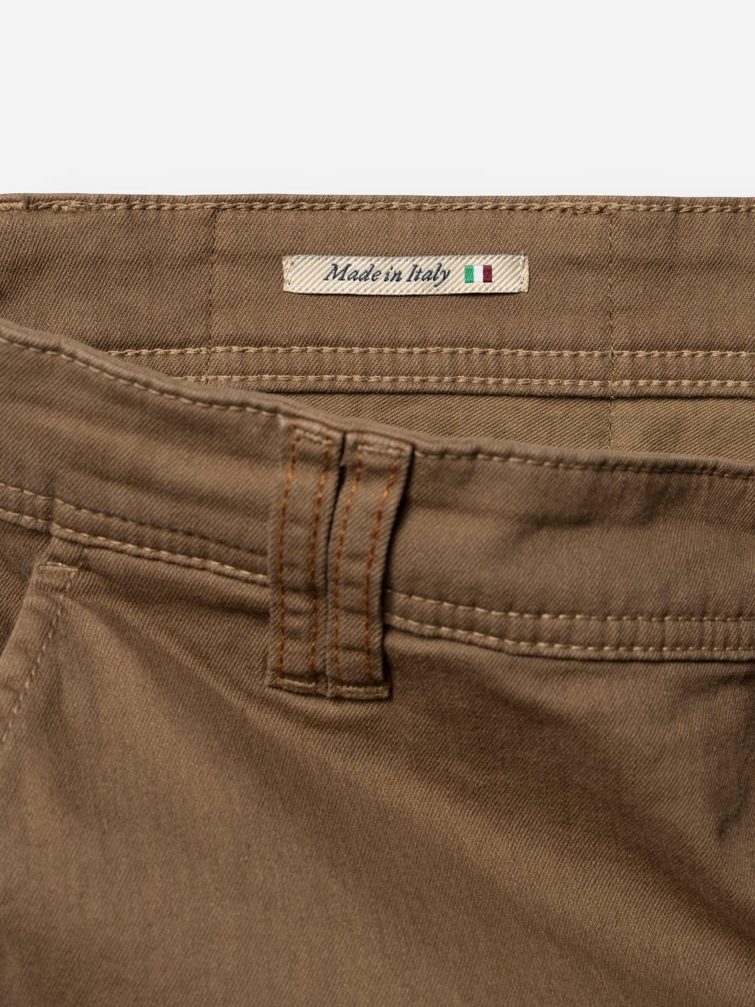 Close-up of Blue de Gênes BGpaulo Pavia 1 V2 Chino pants in Fudge, highlighting a belt loop, pocket seam, and a fabric label reading Made in Italy with a small Italian flag.