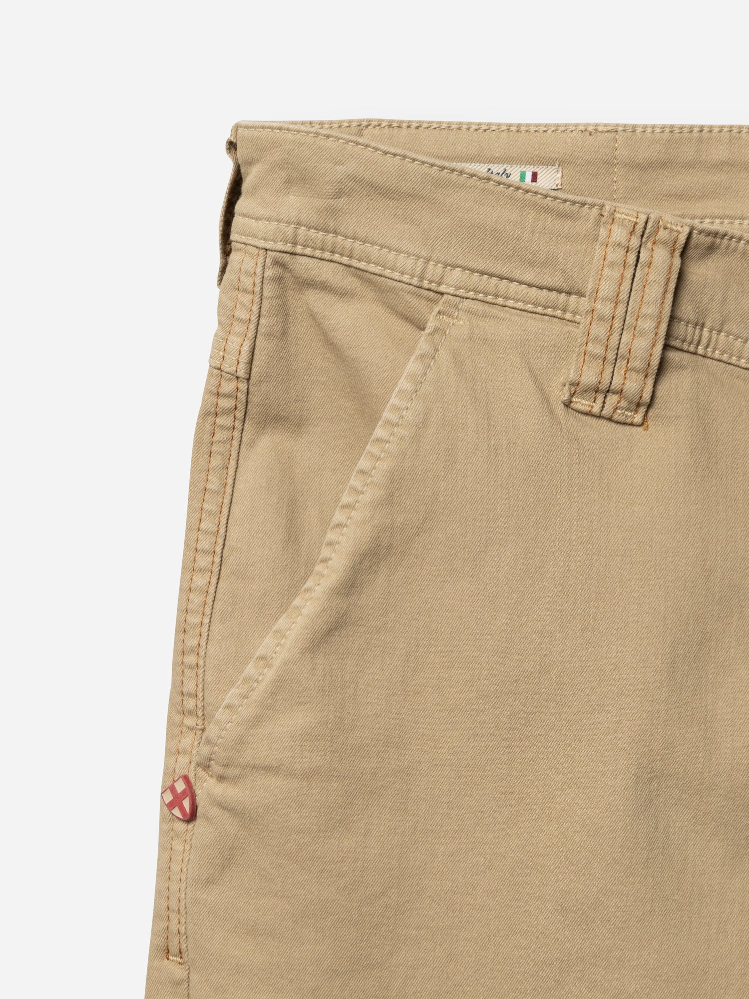 Close-up of the upper section of the Blue de Gênes BGpaulo Pavia 1 V2 Chino in khaki, featuring waistband, belt loop, front pocket, and a red and white tag. Made from soft cotton stretch fabric for comfort.