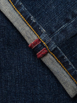 Close-up of the BGvinci Hermina Jeans - Med Used by Blue de Gênes, featuring dark blue selvedge denim typical of regular fit jeans. The image highlights the red and white stitched edge, a yellow thread seam, and fine texture details. Comfort stretch denim is used for enhanced durability and everyday comfort.