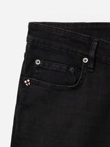 A close-up of the front pocket area of the BGvinci TrueBlack Jeans by Blue de Gênes, showing a small embroidered patch with a white background and red cross near the coin pocket. These regular fit black denim jeans are made from comfort stretch fabric for everyday ease and flexibility.
