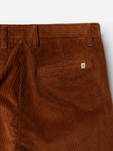 Close-up of the back pocket of Blue de Gênes BGpalco Cord Chino trousers in Ginger Bread Orange, featuring a small metal logo above the pocket. These relaxed fit corduroy pants include belt loops, a distinct corduroy texture, and a gently tapered leg for a modern silhouette.
