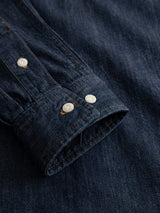 A close-up of the BGgregor Denim Shirt - Denim Blue by Blue de Gênes showcases the denim shirt’s sleeve with white buttons. The detailed stitching and rich texture of the indigo denim fabric emphasize the craftsmanship and quality of this classic cotton shirt.