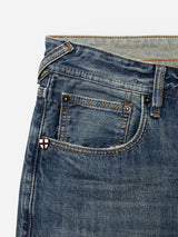 Close-up of BGgiacomo Alfie Jeans - Mid Blue Denim by Blue de Gênes, highlighting the waistband, front pocket, and coin pocket. A small white and red shield-shaped emblem adorns the coin pocket. Orange stitching runs along the seams, reflecting quality craftsmanship and the comfort stretch denim used in these relaxed loose fit jeans.