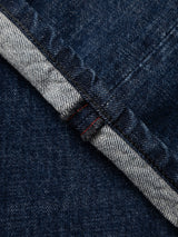 Close-up of the edge of Blue de Gênes BGgiacomo Arthour Jeans in Denim Blue, displaying the fabric’s selvedge seam accentuated by a visible red stitching line. The texture and weave of this comfort stretch denim are clearly depicted, highlighting the quality construction characteristic of these relaxed loose fit jeans.