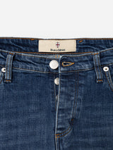 Close-up of the BGrepi Callum Jeans in Mid Blue Denim by Blue de Gênes, highlighting the waistband, belt loops, silver buttons, front pocket, and a white label featuring a red and blue crest with the brand’s name. These regular slim-fit jeans are made from comfort stretch denim for added ease of movement while maintaining the timeless five-pocket design.