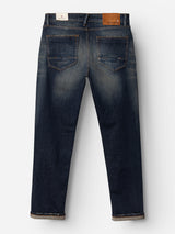 The BGvinci Finlay Jeans - Vintage Wash by Blue de Gênes are shown from the back in a dark blue shade, featuring two rear pockets, subtle fading, and a brown leather patch on the waistband. Crafted from comfort stretch denim for ease of movement, these jeans have a straight-leg cut with slightly rolled-up hems.