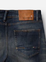 Close-up of the back of Blue de Gênes BGvinci Finlay Jeans in a vintage wash, highlighting a brown leather brand patch above the pocket. These regular fit jeans are crafted from comfort stretch denim and feature visible stitching details.