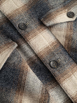 Close-up of the Blue de Gênes BGyodo Check Overshirt in Grey Check, featuring a regular fit with grey and blue plaid wool, metallic buttons, and pocket flaps highlighting visible fabric texture and detailed stitching.