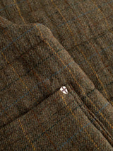 Close-up of the BGalec Skotch Waistcoat in Brown Check by Blue de Gênes, showcasing its checked wool fabric with a subtle plaid pattern and visible stitching, accented by a small metal button featuring a white shield with a red cross design.