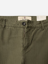 Close-up of the BGmenzo Rory Chino - Army by Blue de Gênes, featuring olive green washed herringbone fabric, a visible zipper, button closure, belt loops, and a Blue de Gênes label on the waistband. Designed in a classic chino fit with a partially visible white tag inside.