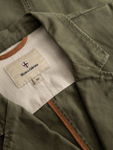 Close-up of the BGgabbiano Rory Blazer - Army by Blue de Gênes, crafted from washed olive green herringbone fabric. The image highlights the inner label—reading Blue de Gênes and size 50 on cream fabric with brown trim—and shows visible stitching that accentuates its unconstructed design.