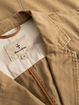Close-up of the BGgabbiano Rory Blazer - Khaki by Blue de Gênes, crafted from washed herringbone fabric in a tan hue. The image highlights the collar, lapel, and inside label featuring the Blue de Gênes logo and a size S tag, with brown trim accenting the blazer’s inner lining.