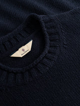 Close-up of the BGgordon Knit in dark navy, a wool sweater by Blue de Gênes with a ribbed crew neckline. The interior collar features a tag with the Blue de Gênes logo, underscoring the refined craftsmanship of this crew neck embroidered sweater.