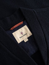 A close-up of the BGmudock Wool Waistcoat in Dark Navy reveals a beige label featuring a shield logo and the Blue de Gênes brand name stitched inside the collar, emphasizing its workwear-inspired design.