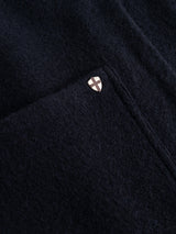 Close-up of the Blue de Gênes BGmudock Wool Waistcoat in dark navy, highlighting its textured fabric reminiscent of classic workwear, with a small shield-shaped pin featuring a white cross on a beige background placed near a seam or pocket.