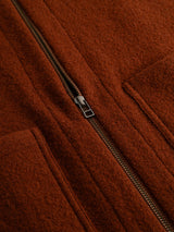 Close-up of the BGmudock Wool Waistcoat in Ginger Bread Orange by Blue de Gênes, featuring a brown textured fabric with a visible metal zipper and two pockets, showcasing the material and stitching details inspired by classic workwear vests.