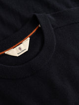 A close-up of the BGhamish Crewneck Knit in dark navy, crafted from fine merino wool by Blue de Gênes, featuring a crewneck design and a distinctive orange stitched accent inside the collar.