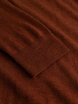 Close-up of the BGhamish Crewneck Knit in Ginger Bread Orange by Blue de Gênes, highlighting the textured merino wool and fine ribbed cuff against a smooth background.