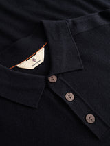 Close-up of the BGigor Polo Knit in Dark Navy by Blue de Gênes, featuring three dark brown buttons and a visible inner tag with a red and blue emblem and the text “Downing Crown” on a cream background.